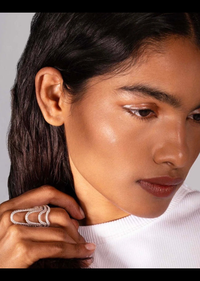 Aveluene Halo Ring pavé mit geschwungenem Design und funkelnden Diamanten an der Hand eines Models